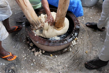 Fufu, a staple made from cassava and plantain, being pounded at the popular Agya Badu 'chop bar'. While two men pound the dough with heavy pestles in alternating rhythmic strokes, a woman deftly turns...