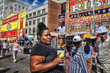 A woman waits in line during ribs festival in downtown.