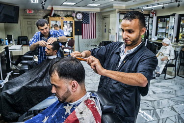 Fatiq, a Yemeni hairdresser, cuts a customer's hair in a barber's shop.