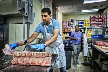 Sadiq, a Yemeni butcher, cuts meat in the shop where he works.