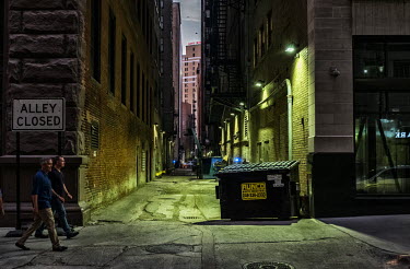A dark alleyway running between skyscrapers.
