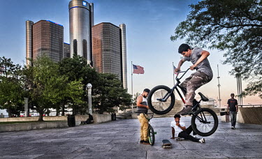 A youth does stunts on his BMX bike near the General Motors headquarters building.