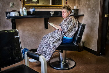 A woman reading the Bible while waiting for a hair cut at Francis Tucci, a Italian hairdresser who has had his business for decades.