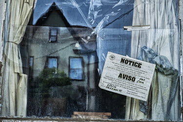 A notice, advising of a violation, stuck to the window of an abandoned house.