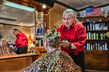 Francis Tucci, a Italian hairdresser who has had his business for decades, cuts the hair of an elderly woman.