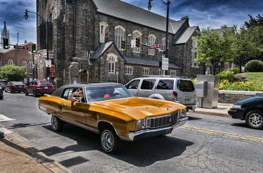 A Hispanic man gives the thunbs up from the passenger seat of a 'pimped' classic American car.