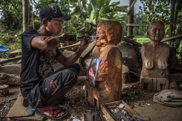 Jefry Maguling carves a Tau Tau for the family of a recently deceased woman. Torajans carve Tau Tau in the likeness of the deceased and place them outside their graves.