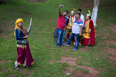 A group of people, some dressed in traditional clothing hired from a kiosk, take a selfie in a park in Shillong.