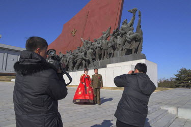 A couple have a wedding picture taken beneath a bronze frieze of soldiers and peasants at The Grand Monument on Mansu Hill.