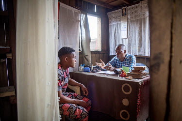 Hosea Sosu, a practitioner of traditional medicine, with a patient in his office/home on the Makoko waterfront, a slum area consisting of wooden buildings on stilts erected on a lagoon.