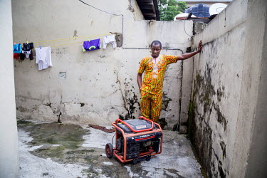 Kom Abasi, an IT specialist working for a bank in the city, stands beside a generator, essential in a city that sufferes constant power outages, in the yard at his home.