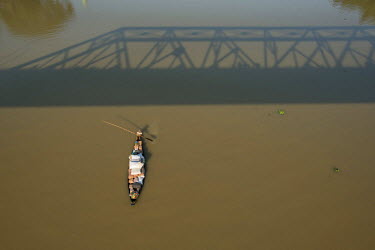 A traditional wooden boat on the Surma River passes under Keane Bridge. The metal bridge was built in 1936 and named after Sir Michael Keane, the English Governor of Assam at the time.
