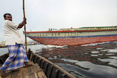 A ferryman avoids a large cargo boat on the Buriganga River at Sadarghat.