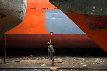 A man painting a newly restored ship at the Keraniganj shipyard on the Buriganga River, where thousands of workers both repair and dismantle ships, as well building new ones from the parts they recycl...