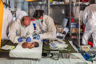 A medical team attends to a baby who was born a few hours earlier on board a boat taking migrants across the Mediterranean Sea. The Spanish navy rescued the boat's occupants and brought them aboard th...