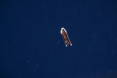 A boat crowded with migrant's drifting in the Mediterranean Sea is viewed from a Spanish navy helicopter flying above it.