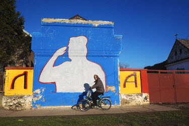 A woman cycles past a mural of war criminal Ratko Mladic.