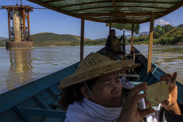 Kachin activist Daw Ja Hkawng takes a picture on her phone near the site of the Myitsone Dam project on the Irrawaddy River.