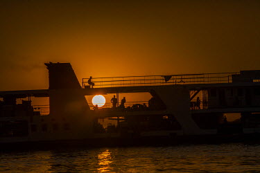 A passenger ship travels on the Irrawaddy River at sunset.
