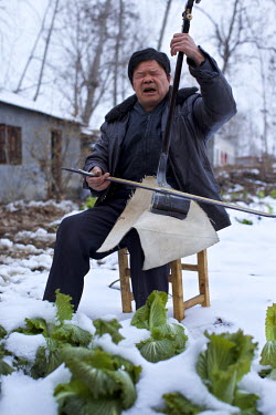 A traditional storyteller practices in a snow covered vegetable field at the Ma Jie folk festival.   For centuries farmers in Henan have gathered during Chinese New Year in the region's wheat fields t...