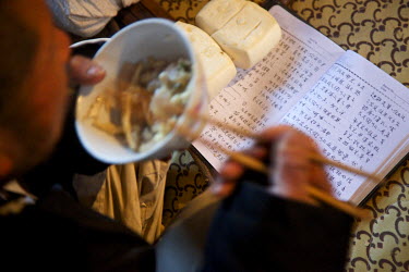 A traditional storyteller practices his lines while eating a meal at the Ma Jie folk festival. For centuries farmers in Henan have gathered during Chinese New Year in the region's wheat fields to list...