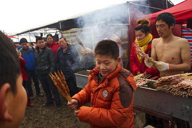 A food stall selling kebabs at the site of the Ma Jie folk festival. For centuries farmers in Henan have gathered during Chinese New Year in the region's wheat fields to listen to bards singing and re...