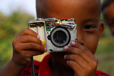 A boy plays with a broken camera.