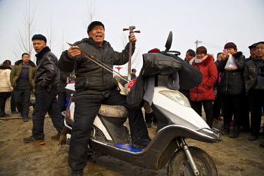 A traditional storyteller performs from the seat of a motorscooter at the Ma Jie folk festival. For centuries farmers in Henan have gathered during Chinese New Year in the region's wheat fields to lis...