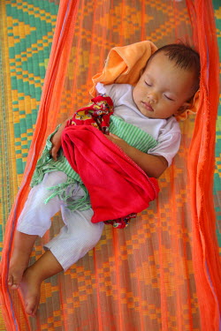 A baby sleeps in a hammock.