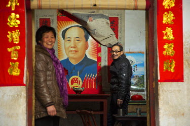 Traditional storyteller Master Li and his wife beside a poster of Chairman Mao.