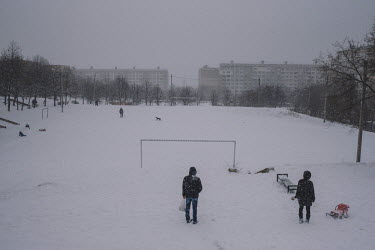 A man walks a dog on a snow covered a football pitch in the Ciocana district.