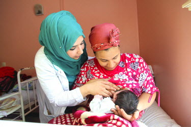 A medic helps a new mother breastfeed her baby in the neonatology unit at the Ghassani Hospital.