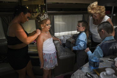 Irish Traveller Viviana and her triplet brothers Richard, John Button and David Sheridan, prepare for her First Holy Communion in her family's trailer, parked in a car park.