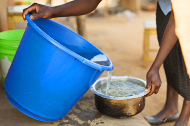 Mercy Chipeta (19) pours water, collected from a nearby river, into a pan to use for cooking.