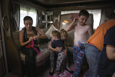 Irish Traveller Georgina hugs her brother Jimmy-Tom in her aunt's trailer while her cousins Richard and John play with Lego and her sister Marika (left) picks sequins from part of an old dress which w...