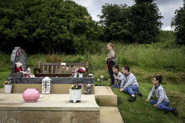 Irish Traveller Viviana and her triplet brothers Richard, John Button and David look at at the grave of a young woman.
