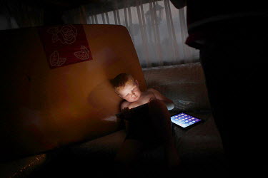 Irish Traveller Dennis Sheridan (6) plays on his iPad in the mobile home where he lives with his family in Essex.