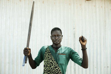 Choul Deng holds the weapon he uses to protect his cattle.