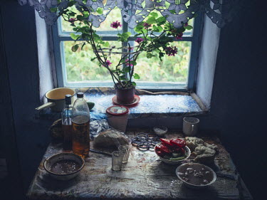 Bread, oil and tomatoes on a table beside a window in a rural home.