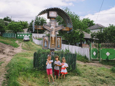 Children standing near crucifix in the village of Horodca.