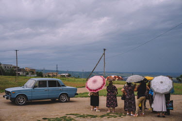 A group of Tartar women standing beneath umbrellas at the roadside in Bakhchysarai's 6th district as a Trabant drives past. In May 1944 Joseph Stalin had the entire Crimean Tatar population deported t...