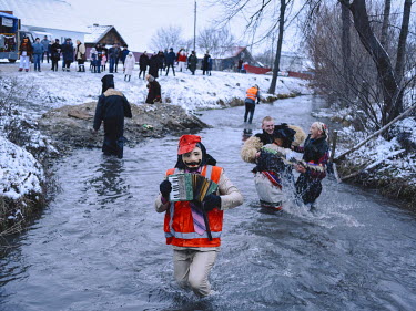 People in costume dance in a stream during the Malanka carnival in the village of Vashkivtsi.