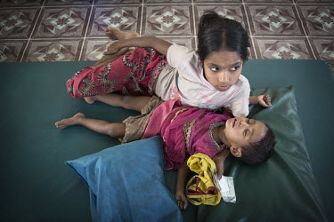 Four and a half year old Jaynuck Begum lies on a mat with her 10 year old sister in the health assessment centre at the Rohingya refugee camp at Kutupalong.