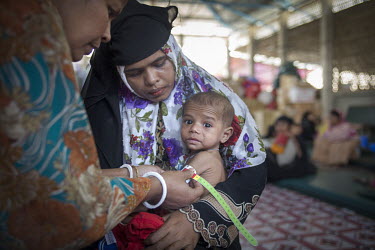 A woman takes a MUAC (mid-upper arm circumference) measurement of seven month old Akabu Rahman at a health assessment centre, where she was born, at the Rohingya refugee camp at Kutupalong.