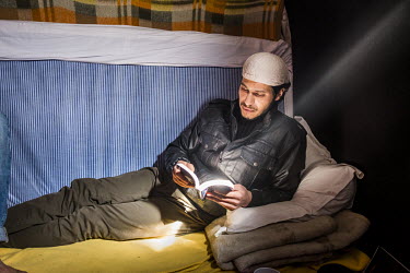 Yassin, a refugee from Damascus reading an Arabic/English dictionary while resting in a makeshift shelter in the so-called 'Jungle' refugee camp. After the camp was demolished he spent time living rou...