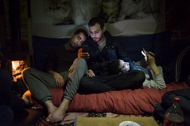 In a makeshift shelter in the so-called 'Jungle' refugee camp, Wessam and Dandan look at old pictures from their hometown Daraa in Syria.