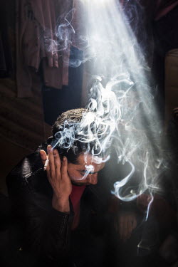 Wessam (21) smoking in his makeshift shelter in the so-called 'Jungle' refugee camp. He fled Syria with his parents just before the war broke out and ended up in in Calais in October 2015. Among the m...