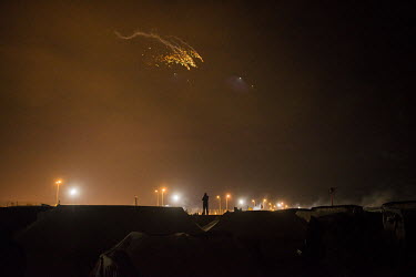 A man stands out against the night sky and the ferry port's lights at the so-called 'Jungle' refugee camp.