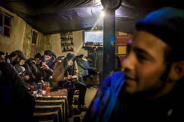 People charging their phones in a makeshift cafe in the so-called 'Jungle' refugee camp.