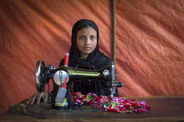 Umme Habiba sits behind a sewing machine at her father's tailoring shop which he set up in the Hakinpara Rohingya refugee camp to where they fled from Myanmar.
